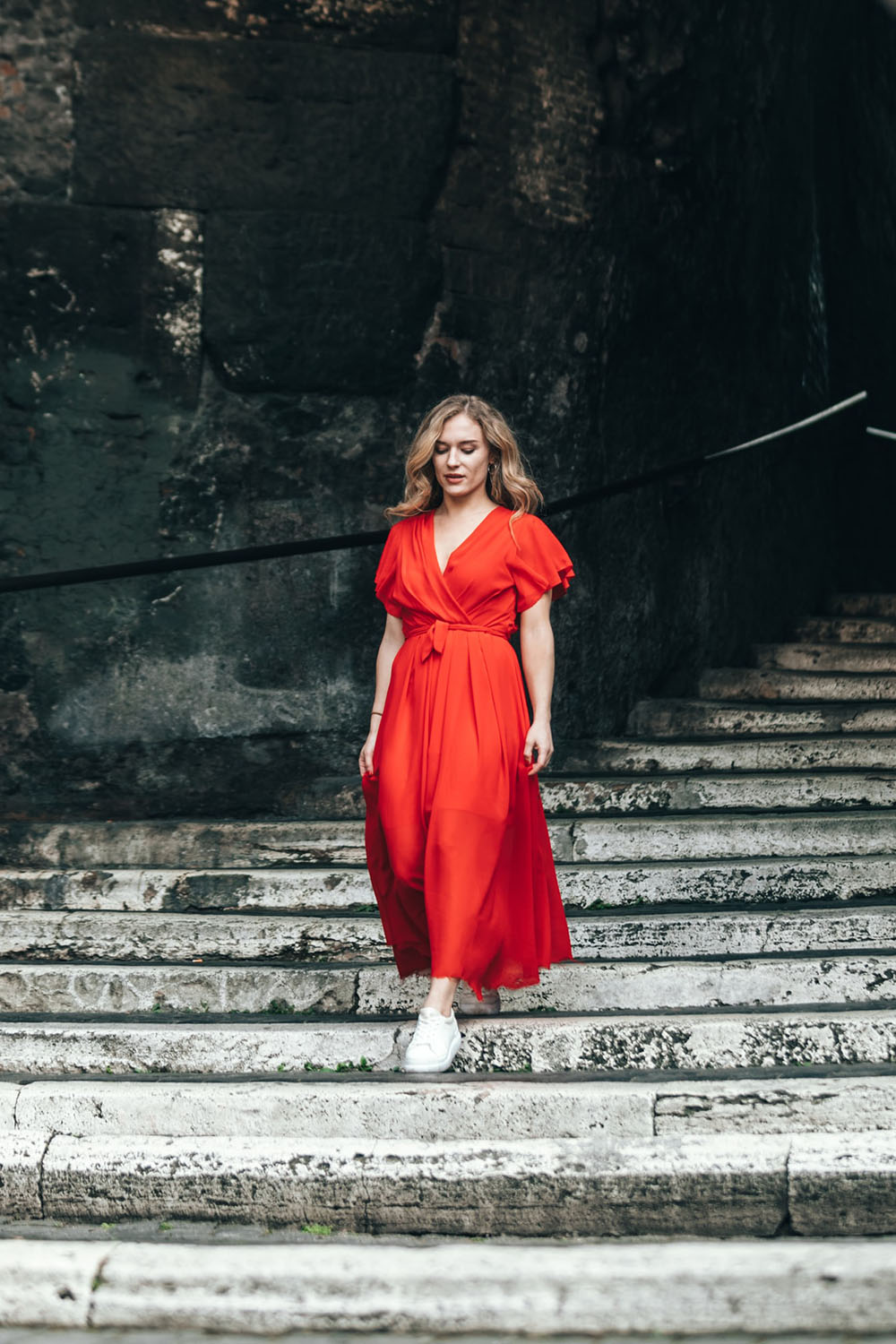 A woman with a red dress on a beautiful staircase in 