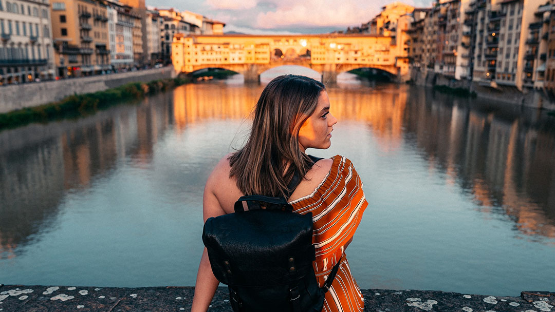 A young woman with a backpack enjoys sunsets in Florence