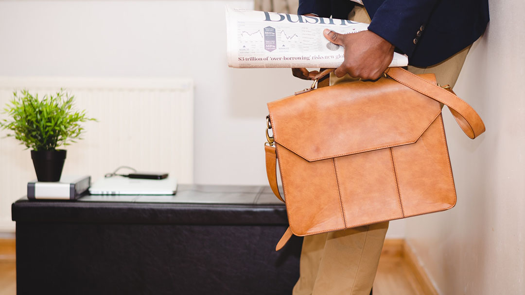 A man holds a new orange leather bag