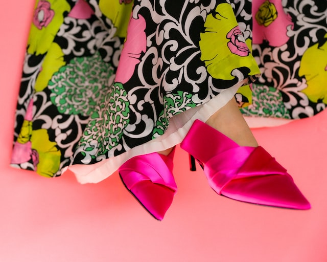 A woman wearing artisans pink shoes and a colorful dress